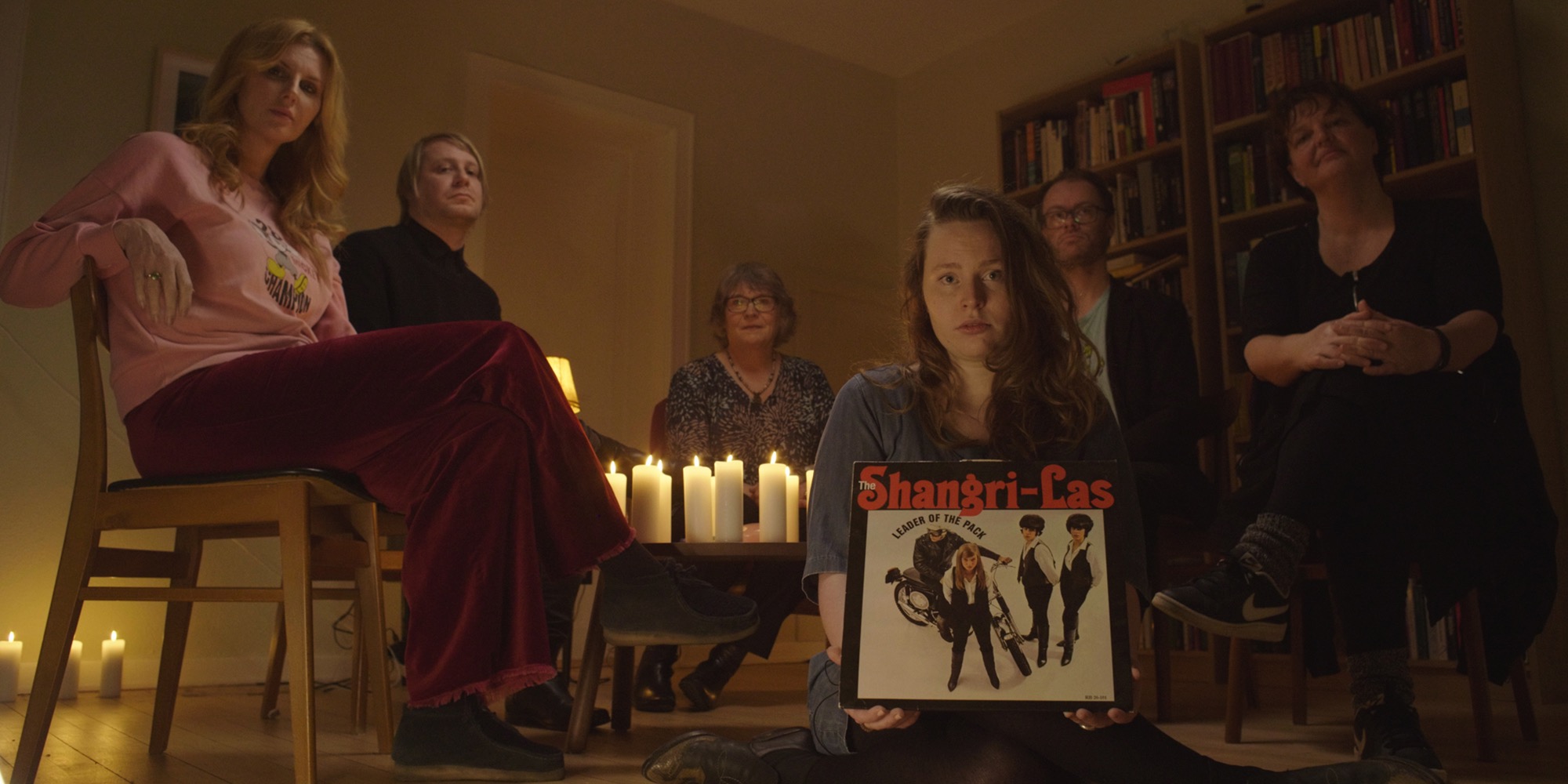 En gruppe mennesker i en stue med en plade og levende lys